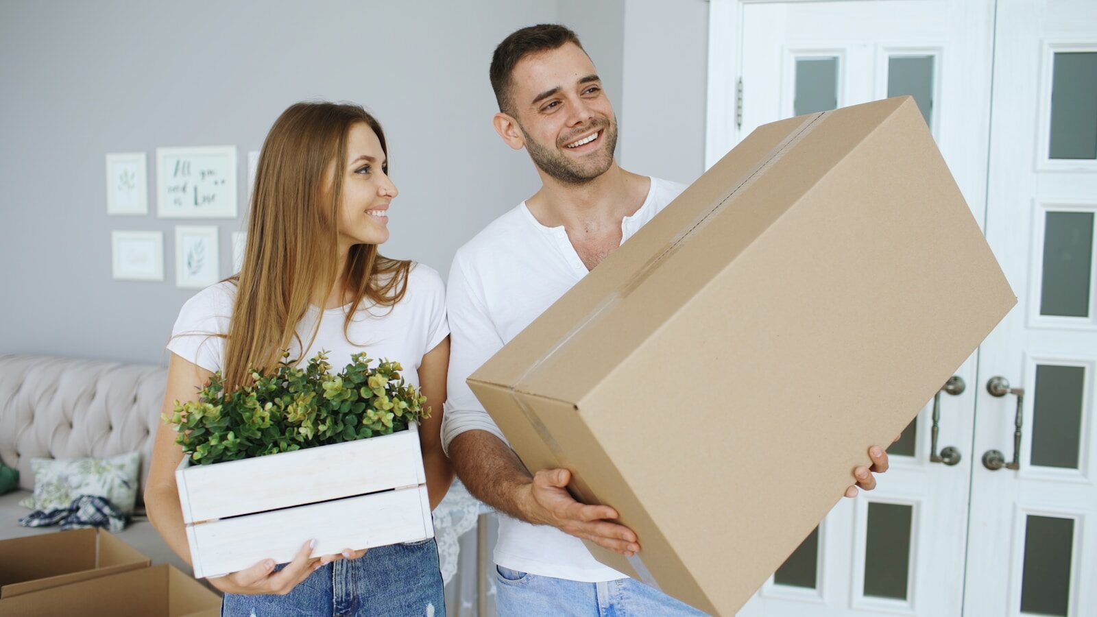 Couple carrying a large box and a plant